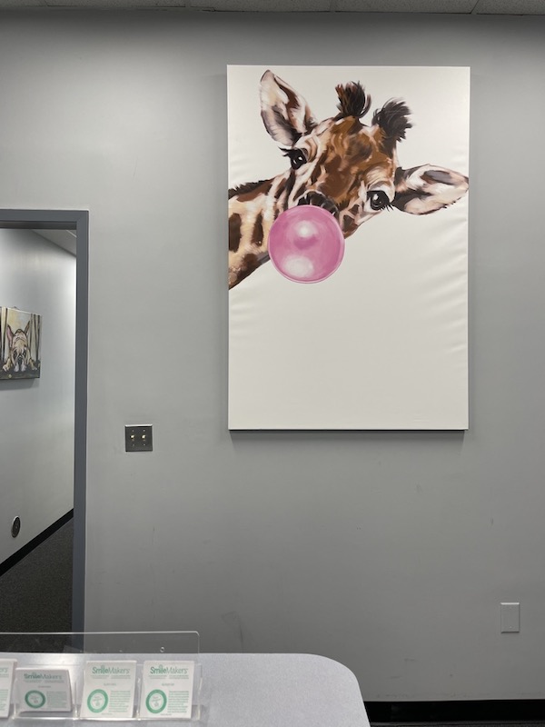 Image of the wall art in Honeygo Pediatrics waiting area of a giraffe blowing a bubble