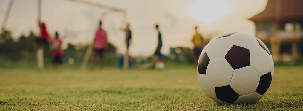 soccerball on a field over looking the goal at sunset